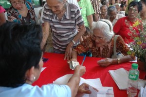 An elderly woman receives her pension from a social worker during an onsite pay-out.