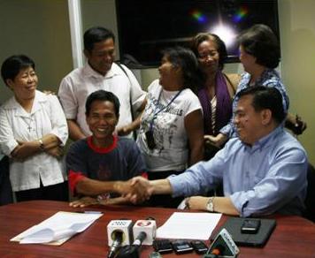 Assistant Secretary Gudmalin and Mr. Trangia shake hand during the signing of the agreements.