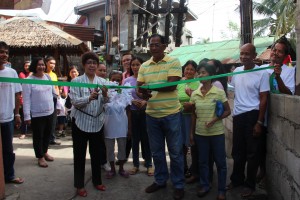 DSWD IV-A Regional Director Leticia Diokno (L) and Barangay Captain Ronald Victor lead the ribbon cutting of the community projects in Ligtong III as DSWD IV-A Assistant Regional Director Floreceli Gunio (left, in white) and barangay residents look on.