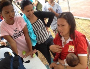 Social worker Evalinda Jimeno breastfeeds a hungry baby of one of the evacuees at newly installed Women Friendly Space the Grandstand.