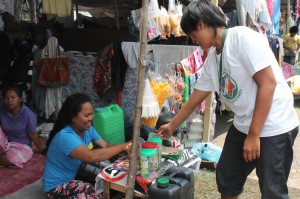 Anisa, attends to a buyer at her make-shift mini store located within her tent area.