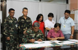 DSWD IX Director Zenaida Arevalo and Col. Reynaldo Mutiangpili sign the 5-page MoA stipulating agreed commitments in the construction of the bunkhouses. Also in photo are Asst. Regional Directors Riduan Hadjimuddin and Consejo Usman, Div. Chief for Protection Services Unit Socorro Rojas and 2 officials from the 52nd Engineering Brigade
