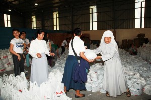 A nun helps carry relief packs.