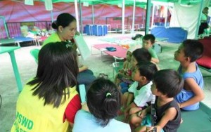 Children-evacuees from Eastern Visayas intently listen to a social worker during a reading and storytelling session at the tent city.