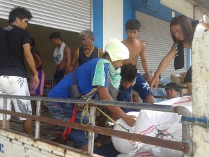 Men help unload sacks of rice at the Tacloban City relief hub.