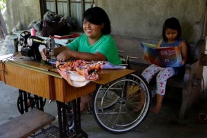 Jane tries on her brand new sewing machine from the local government unit. Sitting behind Jane is six-year old Angel, reading a book while waiting to assist her mother.