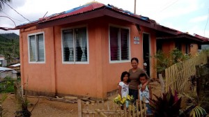 Mary Ann M. Orapa with her children Joylyn Mae and Lester Jade of Barangay San Sebastian, Matag-ob town, Leyte happily pose in front of their core shelter that withstood the rage of ‘Yolanda’.