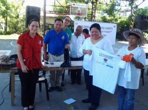 Pantawid Pamilya parent-leader, Victoria Macariola (extreme right), receives her t-shirt, boots, gloves and other gears to be used in the cleaning up of mangroves from Philippine Disaster Recovery Foundation consultant, Christine Reyes (2nd from right).   Others in photo are Dir. Georgina Ann Hernandez (in red vest), DSWD-Field Office VIII Regional Project Development Officer, Hermanito Mangalao (in blue), and Eugene Gonzales (in green) of the Ausaid. 