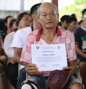  "'Pablo' survivor Julian shows his Certificate of Occupancy from DSWD as proof of home ownership