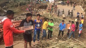 Residents, volunteers, and members of the military work together to carry the DSWD family food packs across the torn-down Dalama Bridge in Munai, Lanao del Norte.