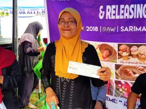 An internally displaced person (IDP) from Marawi City happily shows her P10,000 seed capital fund (in the form of a cheque) provided by the Department of Social Welfare and Development (DSWD). The DSWD has given a total of 364 internally displaced persons from Barangay Basak Malutlut, Marawi City with the livelihood assistance during the latest 'Kawiyagan' by the Task Force Bangon Marawi to help start or rehabilitate their micro-enterprises. Photo from DSWD Sustainable Livelihood Program - Marawi.