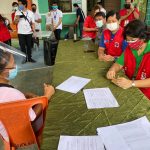 Department of Social Welfare and Development Secretary Rolando Joselito D. Bautista (in blue shirt) joins DSWD Field Office I Regional Director Marie Angela S. Gopalan (in green shirt) and Bacnotan Mayor Francisco Angelito Fontanilla (partly hidden) in handing out emergency shelter assistance to typhoon-affected families in Bacnotan, La Union.