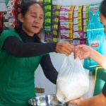 A member of the Pooc Entrepreneur Association hands out a bag of rice to a satisfied customer of their sari-sari store.